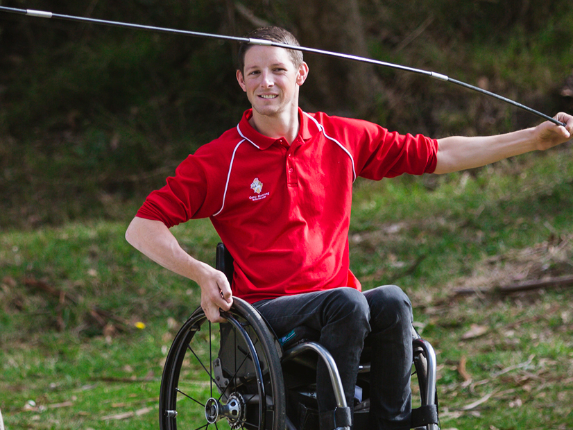 Staff member who uses a wheelchair is setting up an outdoor tent.